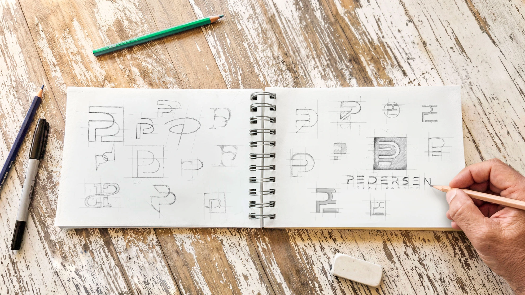 Hand-drawn logo sketches for the Pedersen Real Estate brand identity in an open sketchbook